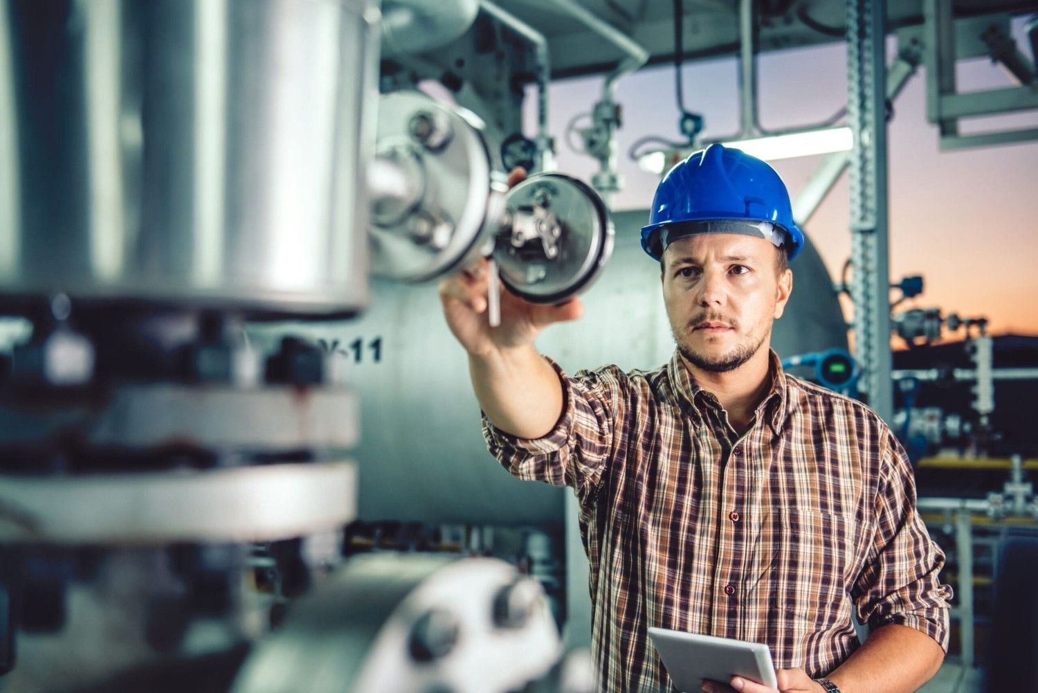 A technician in a hard hat works on a compression system.