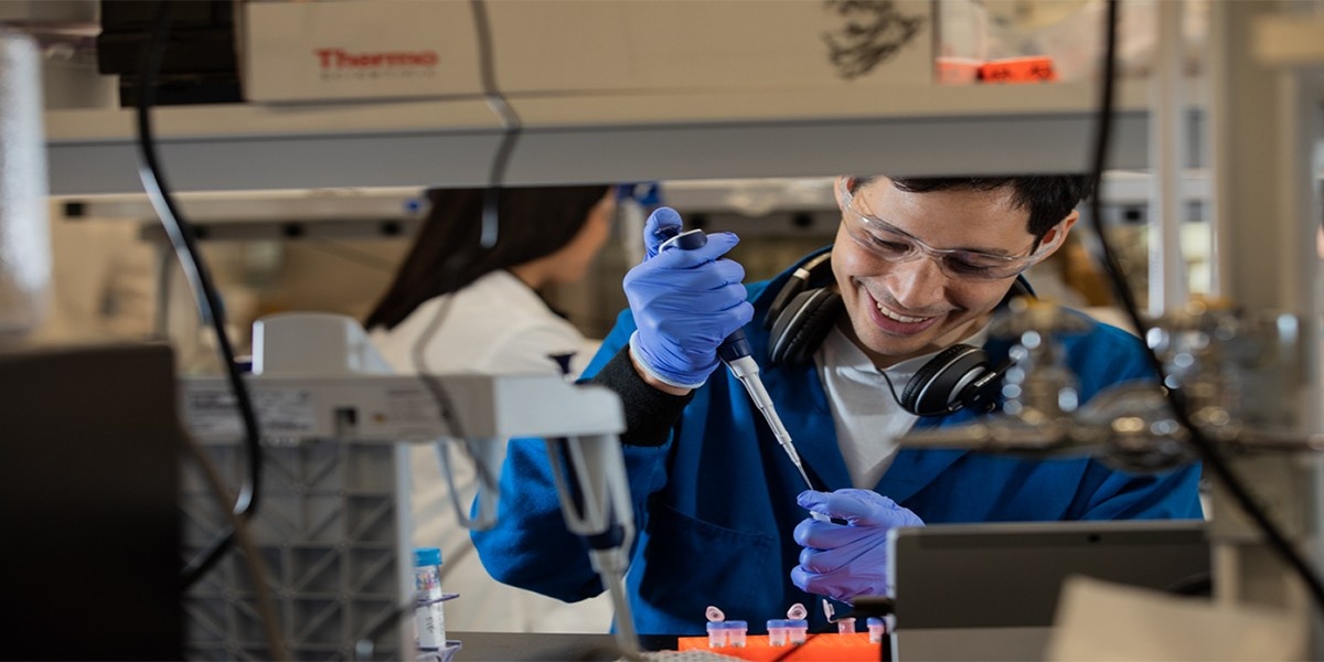 A scientist fills a test tube with a syringe.