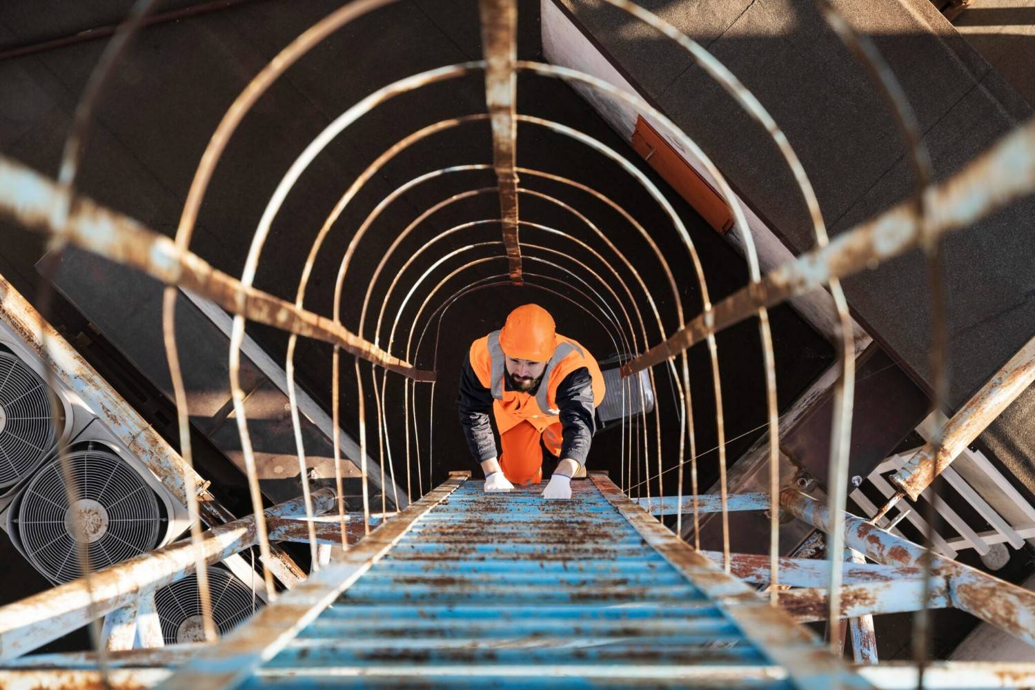 A construction worker climbs up a ladder.