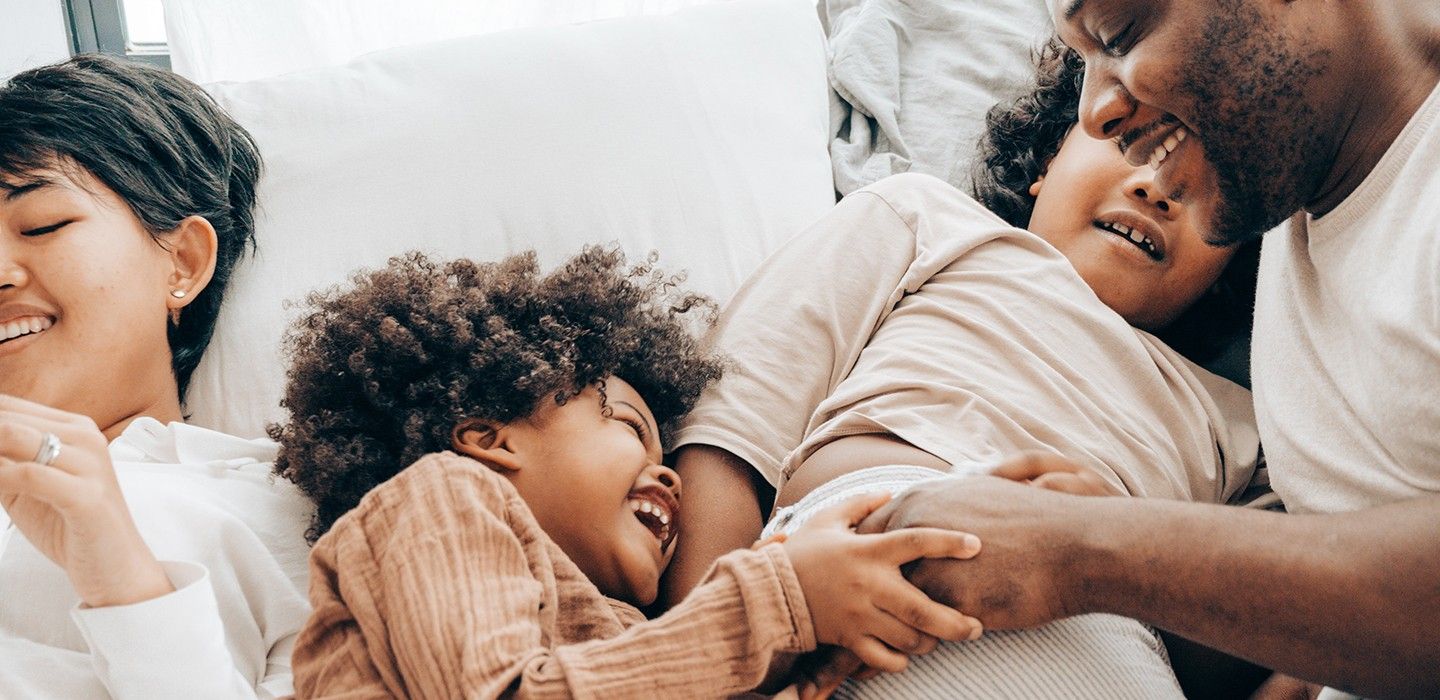 A family of four cuddles on a couch.