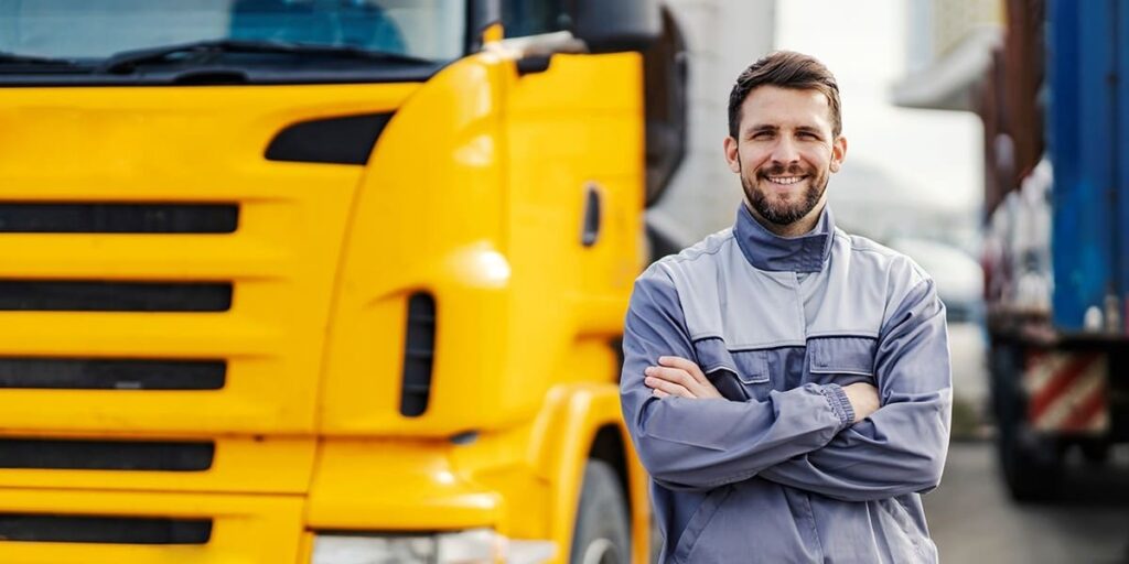 A man standing next to a tractor-trailer smiles at the camera.