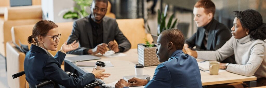 A group of people in business attire sit around a conference table.