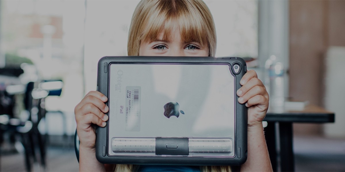 A young child holds a tablet with a protective case.