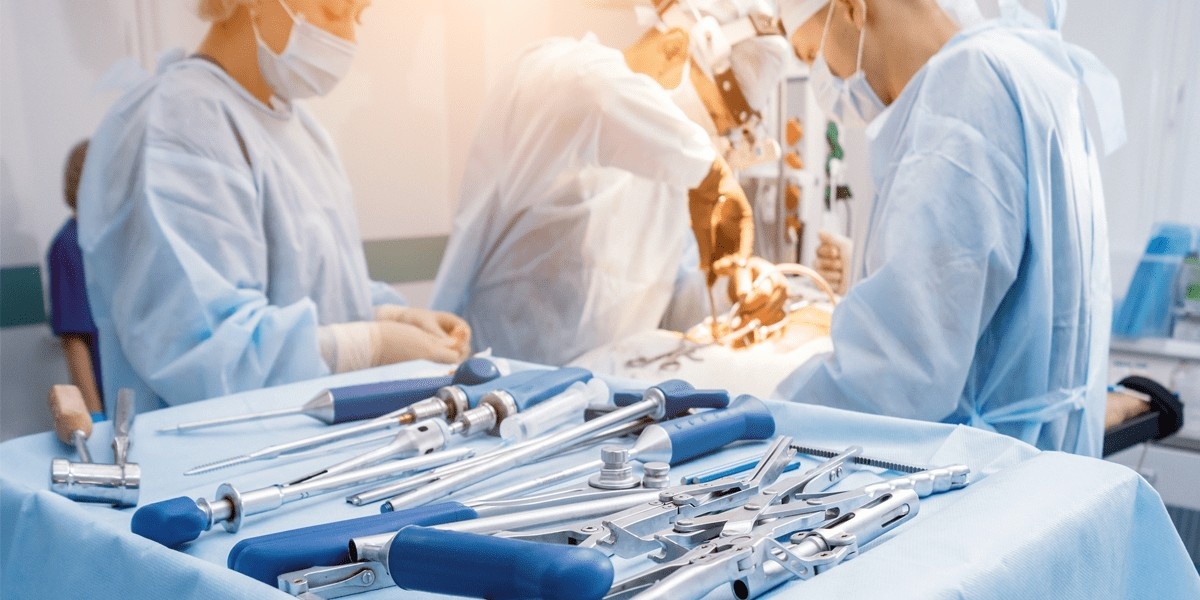 Surgical tools on a desk while surgery is performed in the background.