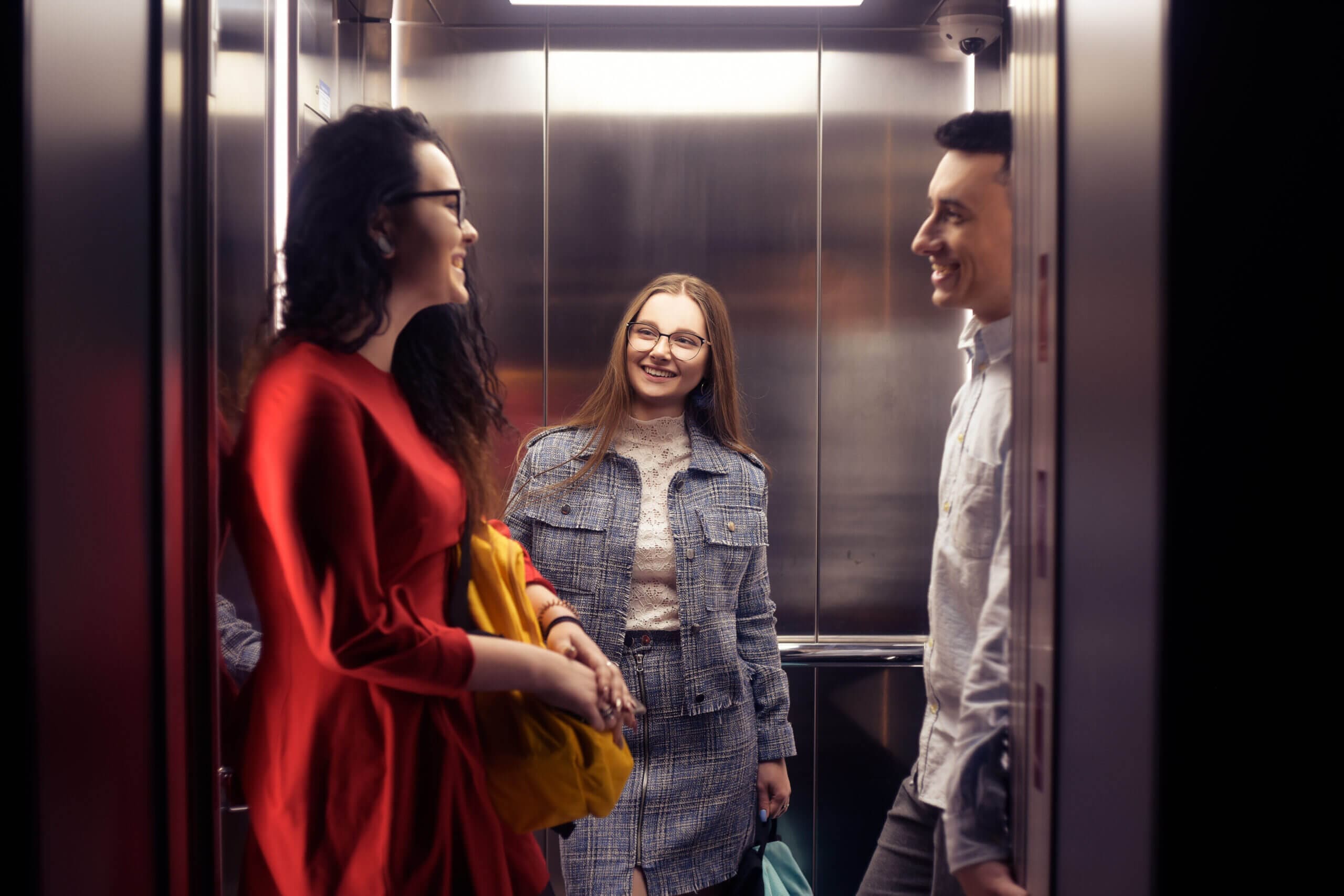 The girls and the guy ride in the elevator.