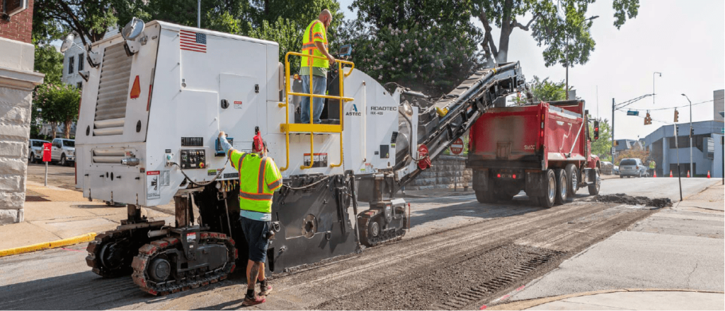 A man in a high-visibility jacket operates a piece of construction equipment.