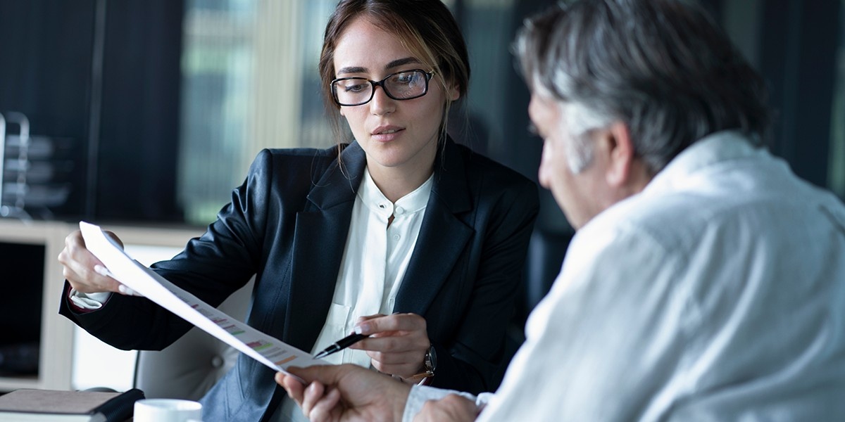 A woman explaining a concept to a man using a paper.