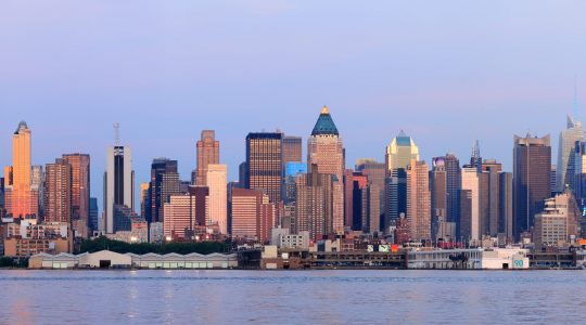 New York City Manhattan sunset panorama with historical skyscrapers over Hudson River viewed from New Jersey Weehawken waterfront at dusk with tranquil blue tone.