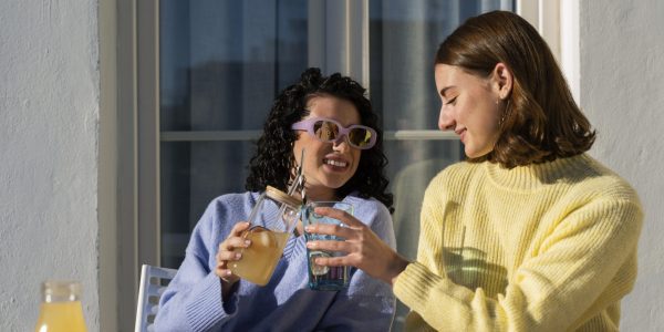 Two young lady enjoy drink in sunlight